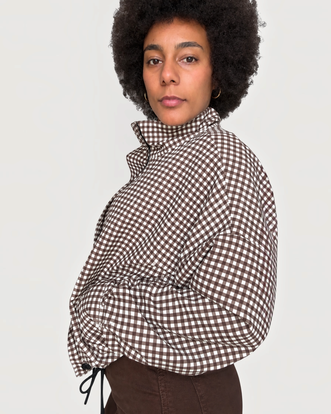 Modelo con chaqueta A F R A A T E L I E R Kaia de cuadros negros y blancos con cuello alto y cremallera frontal