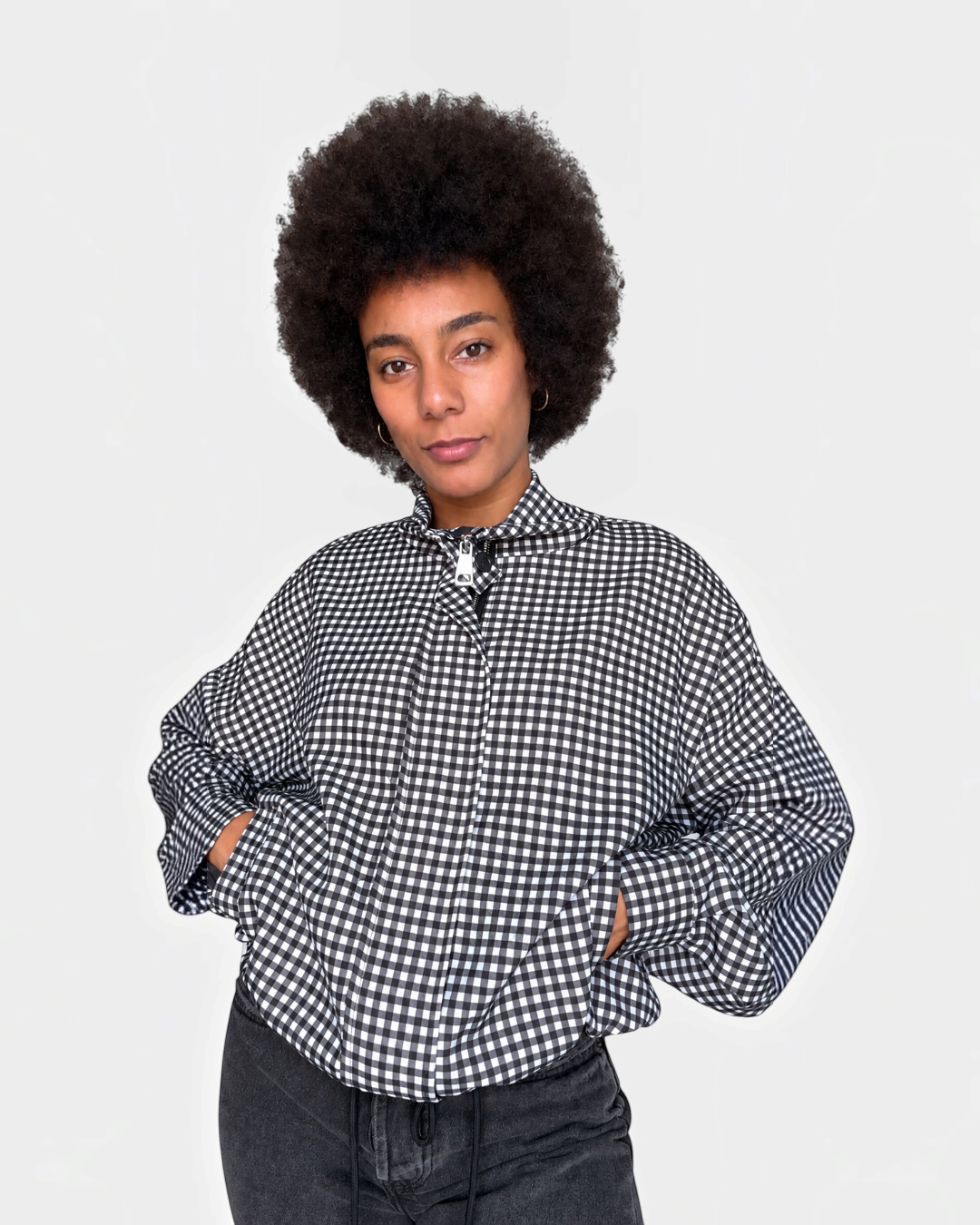 Modelo vistiendo chaqueta A F R A A T E L I E R Kaia negra de cuadros con cremallera y bajo ajustable