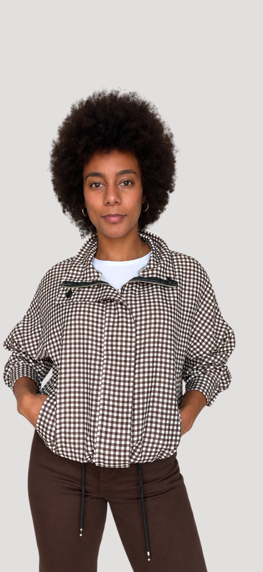 Modelo con chaqueta A F R A A T E L I E R Kaia de cuadros negros, corte amplio, cremallera y bajo ajustable.