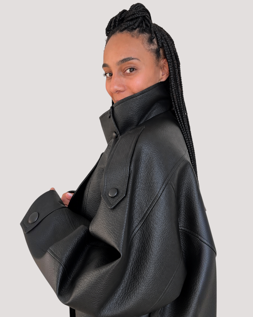Modelo luciendo chaqueta de polipiel negra con cuello alto y botones de AFRA ATELIER