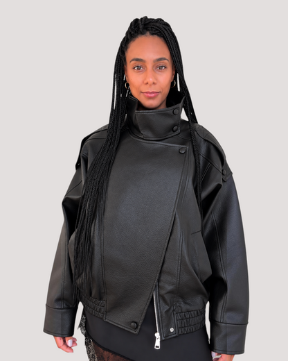 Modelo con chaqueta de polipiel negra de AFRA ATELIER con cuello alto, cierre cruzado y diseño de hombros caídos.
