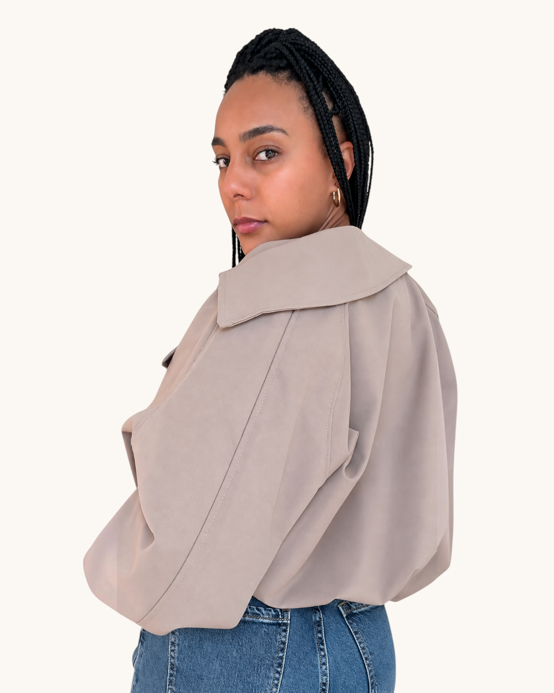 Mujer con trenzas vistiendo una chaqueta bomber beige de AFRA ATELIER con cuello clásico y costuras detalladas