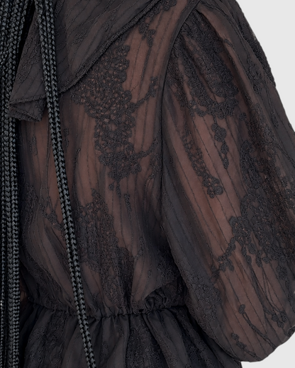 Modelo con blusa negra de encaje transparente AFRA ATELIER con cuello estilo marinero y cintura ajustada