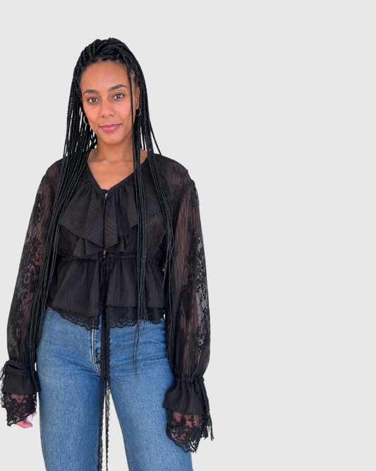 Modelo vistiendo la blusa negra Roma de AFRA ATELIER con encaje, volantes y mangas largas acampanadas.
