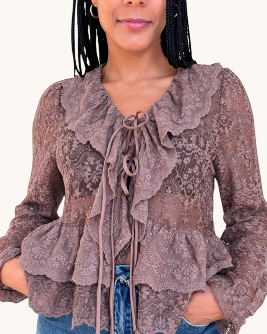 Modelo vistiendo blusa de encaje color marrón con volantes y lazo frontal de AFRA ATELIER sobre fondo blanco