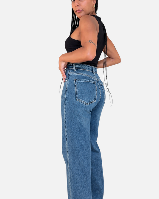 Modelo posando de espaldas con jeans AFRA ATELIER de corte recto y tono azul medio sobre fondo blanco