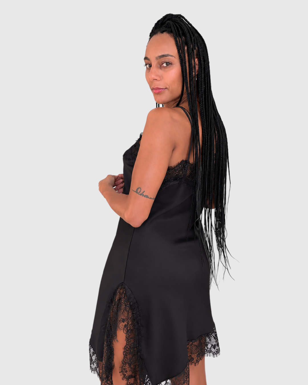 Modelo con vestido lencero negro de satén con detalles de encaje y abertura lateral de AFRA ATELIER