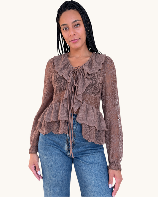 Modelo vistiendo blusa de encaje color marrón con volantes y lazo frontal de AFRA ATELIER