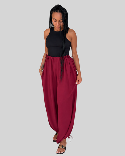 Modelo vistiendo pantalón bombacho AFRA ATELIER color burdeos con lazadas ajustables en cintura y tobillos