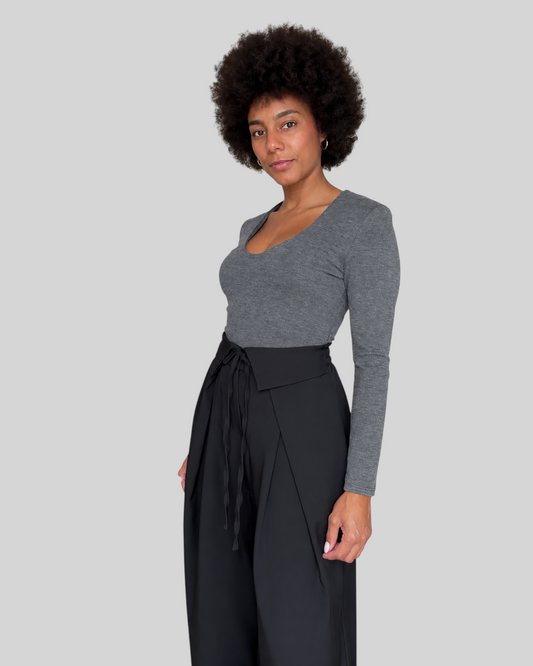 Modelo con pantalón negro Moka de A F R A A T E L I E R y camiseta gris de manga larga sobre fondo blanco