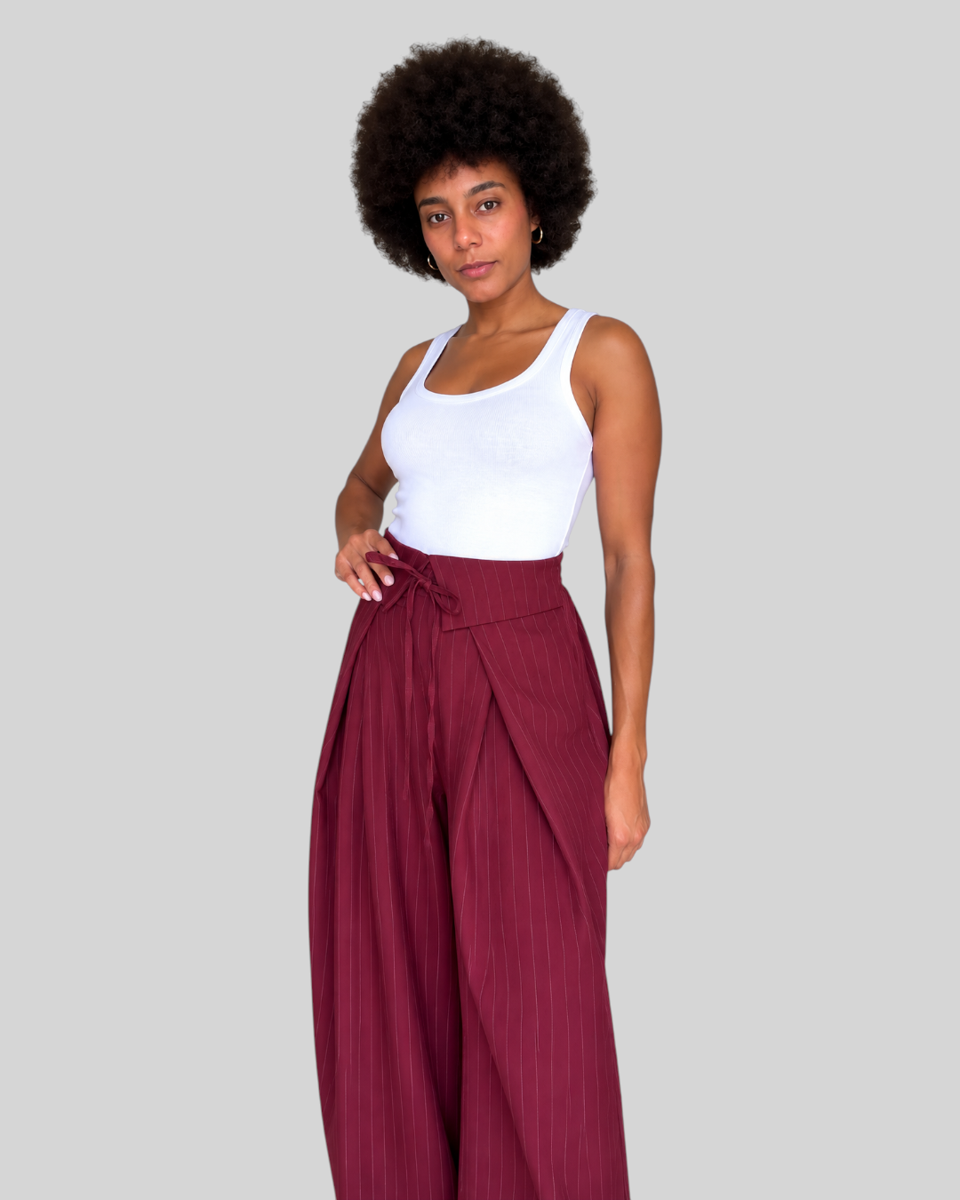 Modelo con pantalón A F R A A T E L I E R de pierna ancha, color burdeos con rayas diplomáticas y cintura cruzada