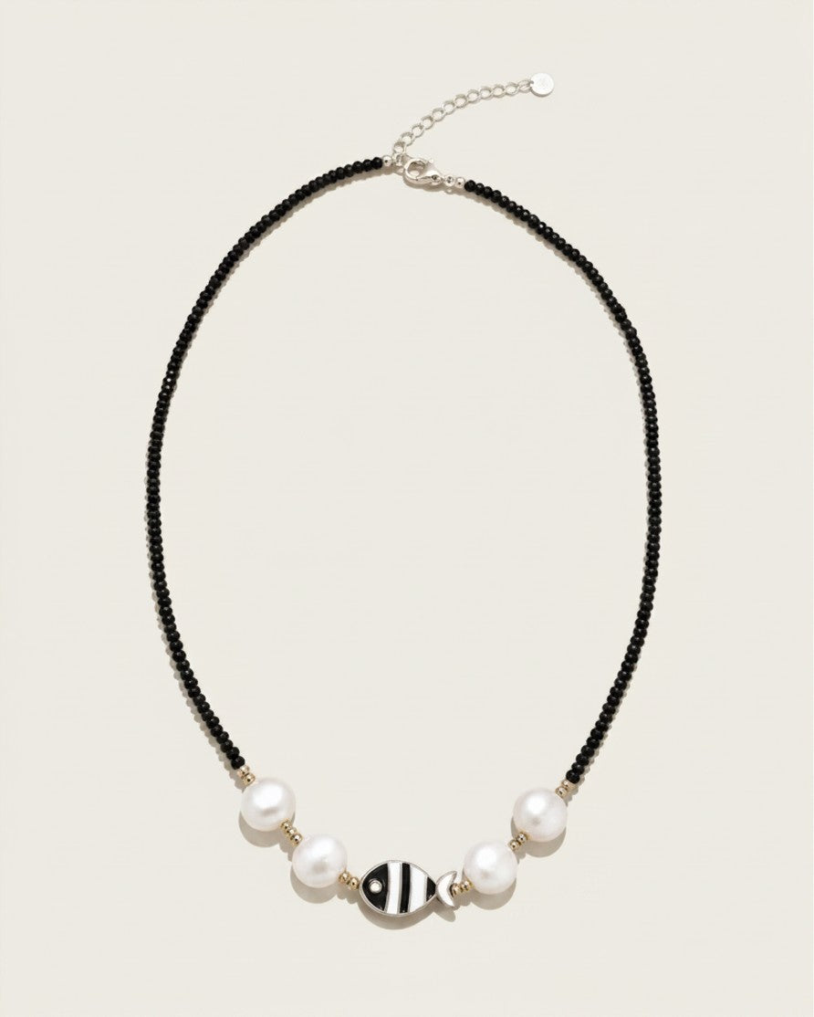 Collar Cala de A F R A A T E L I E R con cuentas negras, perlas blancas, detalles dorados y colgante de pez en acero