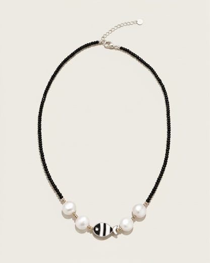 Collar Cala de A F R A A T E L I E R con cuentas negras, perlas blancas, detalles dorados y colgante de pez en acero
