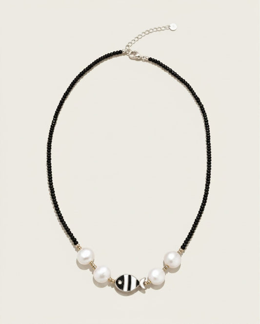 Collar Cala de A F R A A T E L I E R con cuentas negras, perlas blancas, detalles dorados y colgante de pez en acero