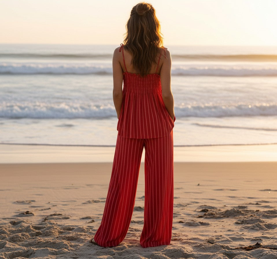 Conjunto A F R A A T E L I E R Famara de rayas rojo y rosa con top de tirantes y pantalón wide leg en la playa