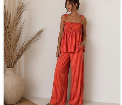Modelo vistiendo el conjunto Famara de A F R A A T E L I E R, top de tirantes y pantalón ancho a rayas naranjas y rosas