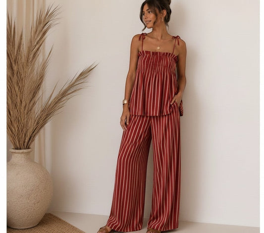 Modelo vistiendo el conjunto Lía de A F R A A T E L I E R, top de tirantes y pantalón ancho a rayas rojas y blancas.