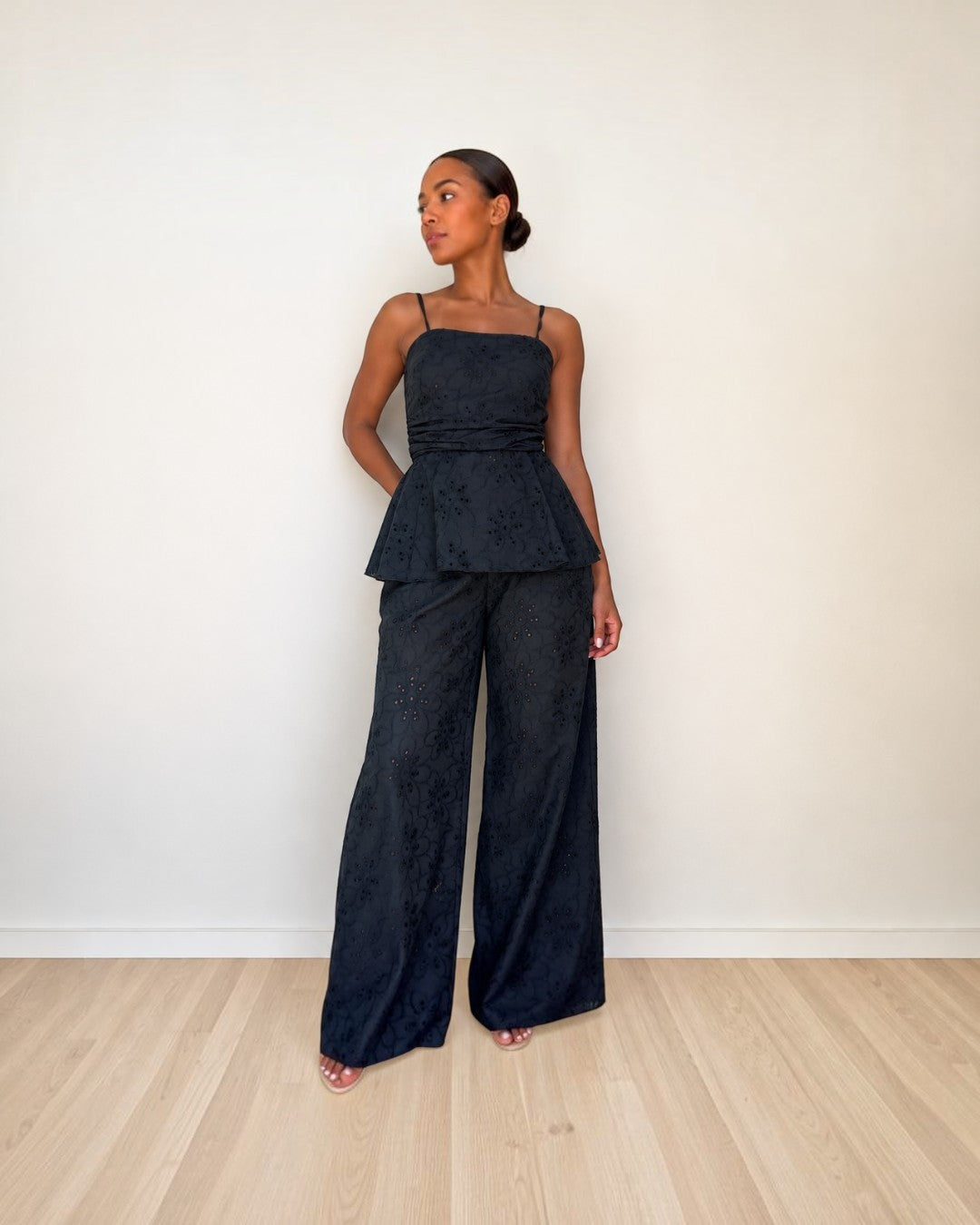 Modelo vistiendo conjunto A F R A A T E L I E R negro de algodón con top peplum y pantalón ancho de encaje floral